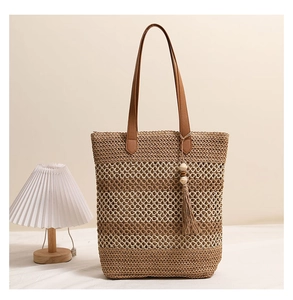 Detail der gewebten Strohtasche mit Ledergriffen und Quastenanhänger im Boho-Stil