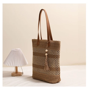 Detailaufnahme der gestreiften Strohtasche mit Quastenanhänger und Ledergriffen