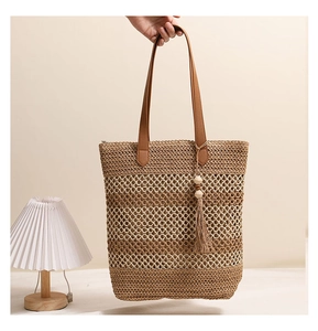 Detail der mehrfarbig gestreiften Strohtasche mit Ledergriffen und Quastenanhänger