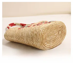 Detailed macro view of the oval hand-woven base of the straw beach bag with embroidery