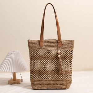 Gestreifte Strohtasche mit braunen Ledergriffen und Quasten für den Strandurlaub