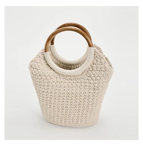 Detail of cream woven tote bag featuring textured knit patterns and round wooden handles