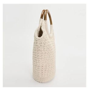 Detail of cream woven tote bag featuring textured crochet and round wooden handles