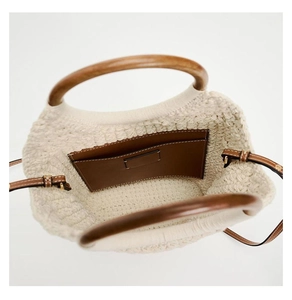 Detail view of woven cotton tote bag with wooden handles and interior leather pocket