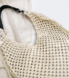 Detail of hollow woven cotton bag with black leather handle and stylish fringe trim