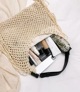Detail of hollow mesh crochet weave and long tassels on beige cotton beach shoulder bag