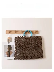 Detail of square woven straw bag featuring hollow diamond mesh and blue round handle