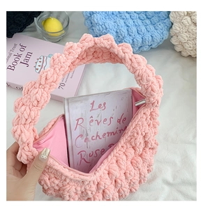Detail of pink hand-woven crochet bag featuring a silver zipper and soft popcorn texture