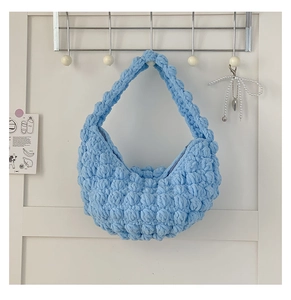 Detail of light blue handmade chunky knit handbag with bubble crochet texture and soft yarn