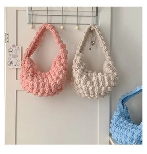 Detail of handmade knit hobo bag featuring 3D puff bubble stitch in pastel pink and blue