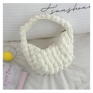 Detailed close-up of white chunky knit crescent handbag with 3D popcorn texture and zipper