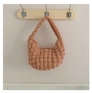 Close-up of pink handmade crochet straw bag with popcorn texture hanging on a wall hook