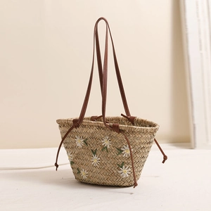 Floral embroidered straw tote bag with brown leather straps for beach vacations