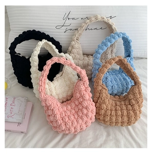 Detail of colorful popcorn stitch hand-knitted bags with soft texture and metal zipper