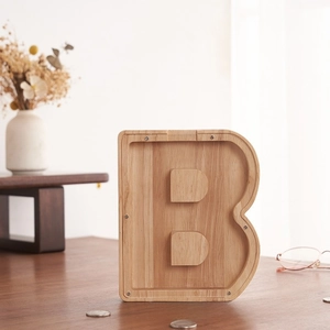Detalle de hucha de madera en forma de B con panel acrílico y grano de madera natural
