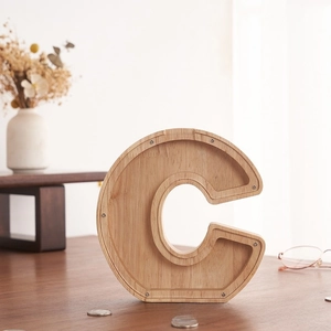 Detalle de hucha de madera en forma de C con panel de acrílico y monedas a la vista