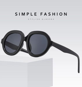 Detail view of bold black oversized sunglasses on a minimalist white geometric stand