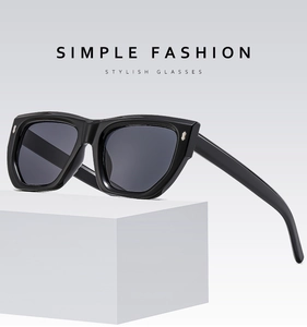 Detail of black square sunglasses with metallic rivets on a minimalist white stand