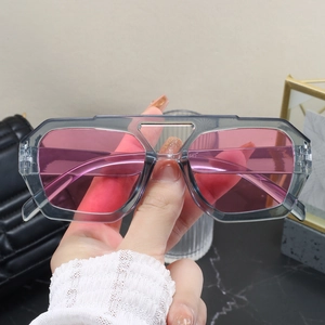 Detailed shot of large grey translucent frame sunglasses with pink tinted lenses