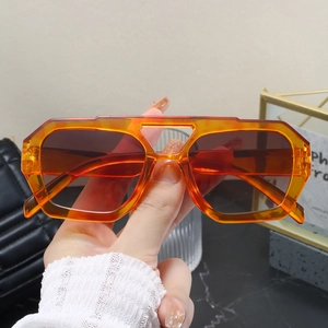 Close-up of translucent orange hexagonal sunglasses with reddish-brown gradient lenses