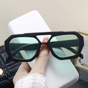 Detail of double bridge sunglasses with green lenses and white textured case