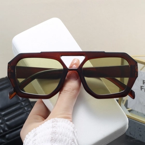 Detail of amber tortoiseshell double-bridge sunglasses with yellow lenses being held