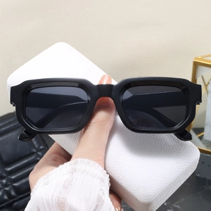 Détail de lunettes de soleil rétro à monture épaisse noire brillante sur un étui blanc