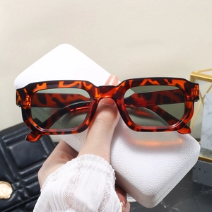 Détail de lunettes de soleil rétro écaillées près d'un étui en cuir blanc