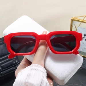 Gros plan de lunettes de soleil rectangulaires rouges rétro sur un étui avec accessoires