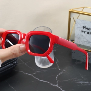 Détail des lunettes de soleil carrées rouges rétro avec verres foncés à la main