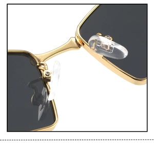 Detail of golden metal sunglasses bridge with clear silicone nose pads and dark lenses