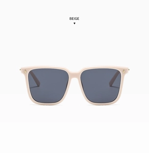 Detail view of beige square sunglasses featuring gold metal rivets and dark grey lenses