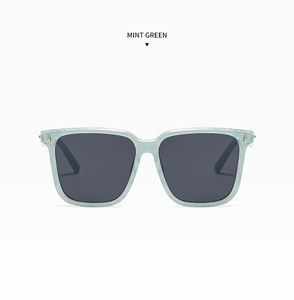 Detail view of mint green square sunglasses with gold metal studs on a white background
