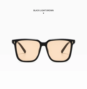 Detail of square black sunglasses with light brown lenses and silver rivet accents