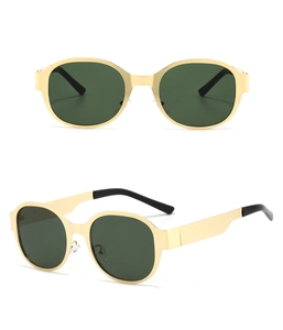 Detail showing oversized gold metal frames and dark green lenses with wide temples