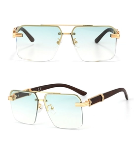 Detailed view of blue gradient lenses with gold C-shape metal hardware on wood grain temples