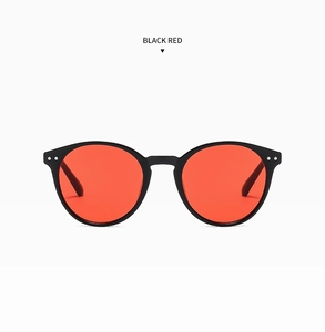 Gros plan sur des lunettes de soleil rondes noires rétro avec verres rouges et rivets