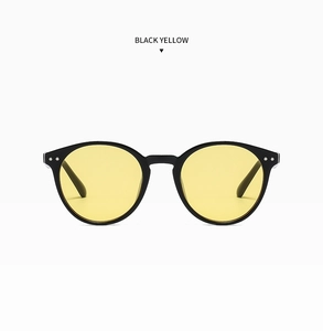 Détail de lunettes de soleil rondes noires avec verres jaunes et rivets argentés chic