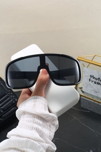 Detail of matte black athletic sports sunglasses with dark grey shield lens and logo on arm