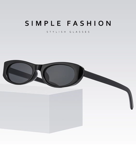 Detail of oval black Y2K sunglasses placed on a minimalist white geometric platform