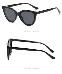 Detail view of glossy black cat-eye sunglasses with dark grey lenses and sleek frames