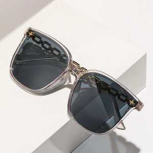 Occhiali da sole oversize grigi con borchie a stella dorate su gradini bianchi