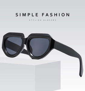 Détail de lunettes de soleil avant-garde à monture noire sur un support géométrique blanc