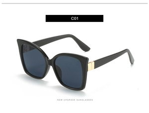 Detail showing glossy black square frame sunglasses with golden metal hinge accent