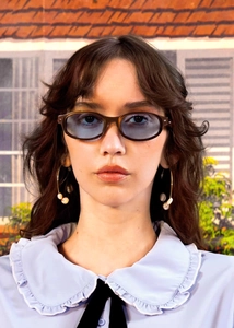 Close-up of vintage oval tortoiseshell sunglasses with light blue lenses on a model