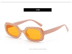 Detailaufnahme der ovalen Sonnenbrille mit orangefarbenem Wellenmuster am Brillenrahmen