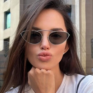 Close-up of model wearing oval punk sunglasses with silver frame and double bridge