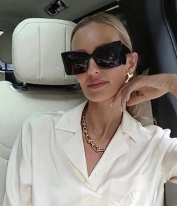 Lunettes de soleil carrées oversize à branches larges portées par un mannequin en voiture
