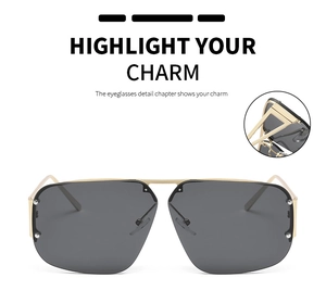 Detail view of large square sunglasses with gold metal frame and dark grey lenses