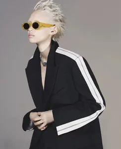 Close-up of oversized yellow transparent sunglasses worn with a black striped blazer